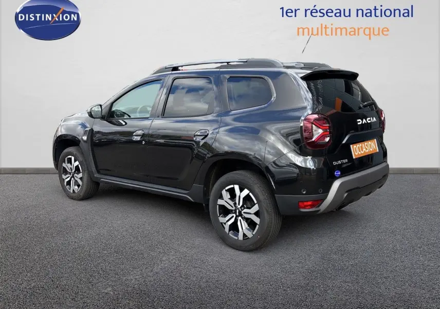Vue 3/4 arrière droite d'un Dacia Duster noir 2024 avec jantes bi-ton et logo visible sur le hayon.