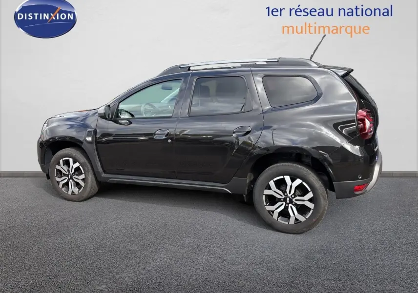Profil droit du Dacia Duster noir 2024 avec jantes bi-ton et toit équipé de barres de toit.
