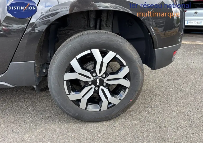 Gros plan sur la roue arrière droite du Dacia Duster noir 2024 avec jante alliage bicolore distinctive.