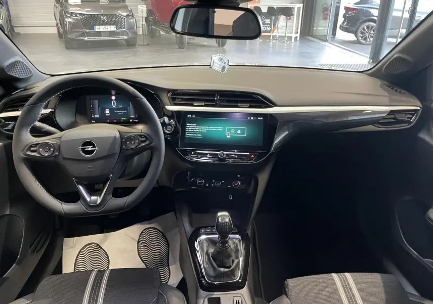 Intérieur avant de l'Opel Corsa blanc 2026, volant cuir, écran tactile 10 pouces et levier de vitesse manuel visible.