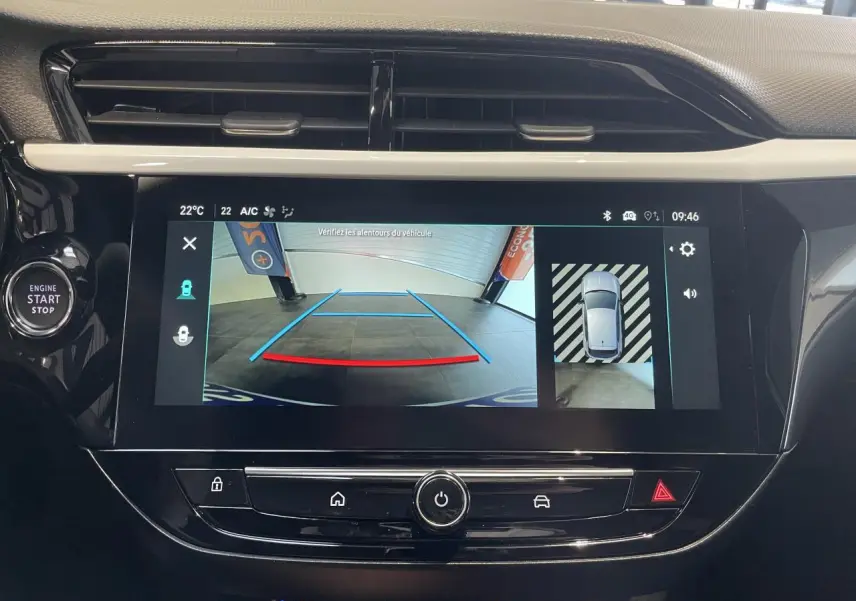 Écran tactile central affichant la caméra de recul panoramique dans l'habitacle noir de l'Opel Corsa blanche.