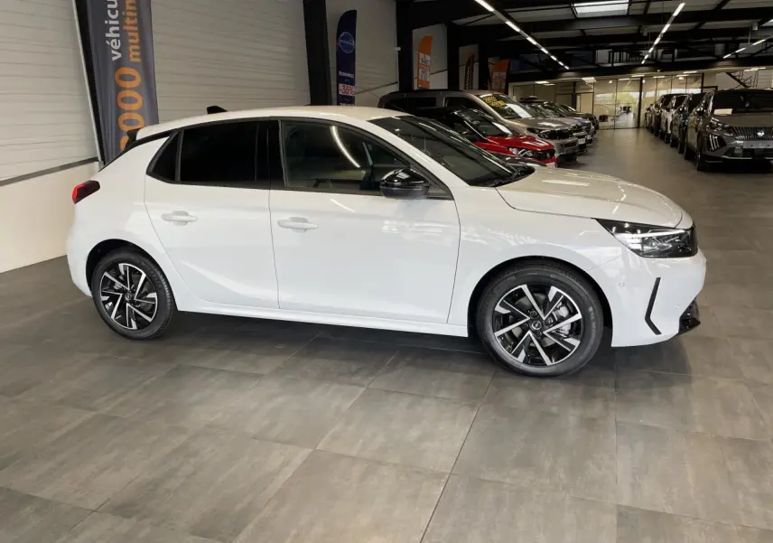 Opel Corsa blanche vue de profil côté gauche en intérieur, avec jantes alliage noires et vitres surteintées.