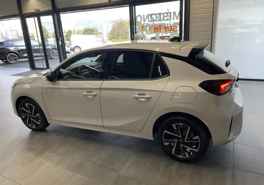 Opel Corsa blanc vue de profil côté gauche en intérieur, vitres surteintées et jantes alliage noires.