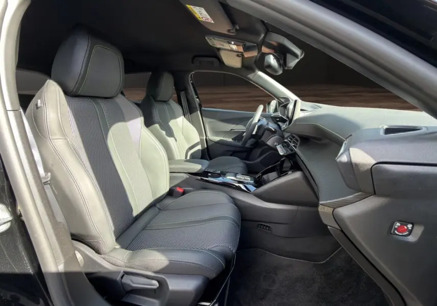 Intérieur avant droit du Peugeot 2008 Hybrid 145 e-DCS6 GT noir, sièges cuir noirs avec surpiqûres contrastées.