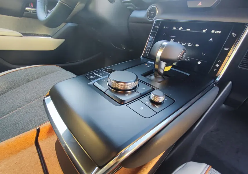 Console centrale vue de près avec levier de vitesses et commandes rotatives dans l'habitacle du Mazda MX-30 rouge métal 2023.