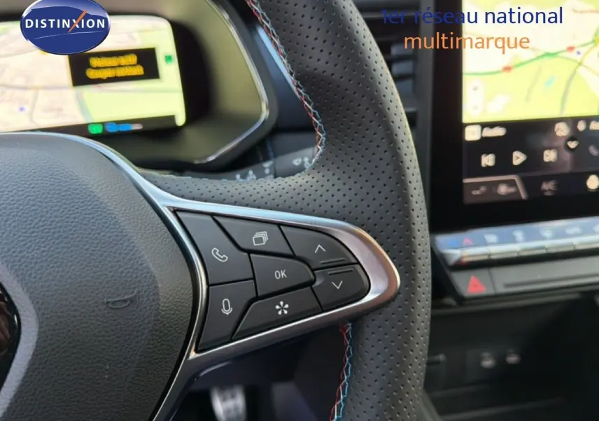 Gros plan sur le volant perforé avec commandes intégrées et tableau de bord numérique du Renault Captur blanc nacré 2025.