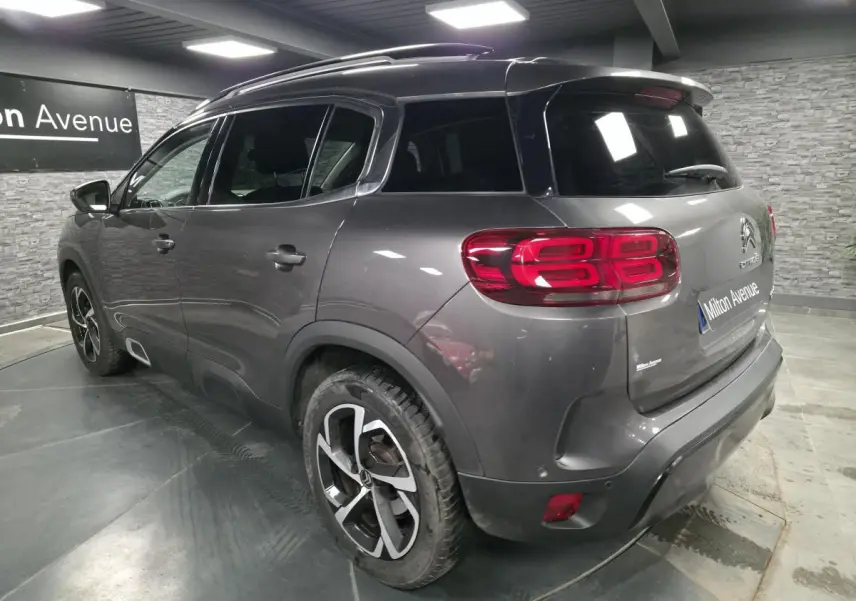 Vue 3/4 arrière droite d'un Citroën C5 Aircross gris métallisé avec jantes alliage et vitres teintées.