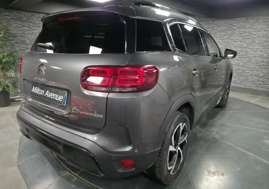 Vue 3/4 arrière droite d'un Citroën C5 Aircross gris métallisé avec feux arrière LED et jantes alliage noires.
