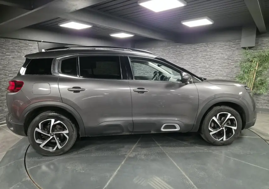 Profil côté droit du Citroën C5 Aircross gris métallisé avec jantes alliage et barres de toit noires.
