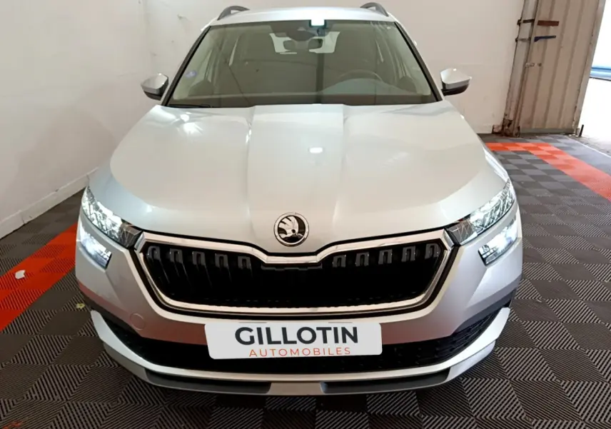 Vue frontale d'un Skoda Kamiq gris clair 2022 avec calandre noire et phares LED allumés dans un garage.