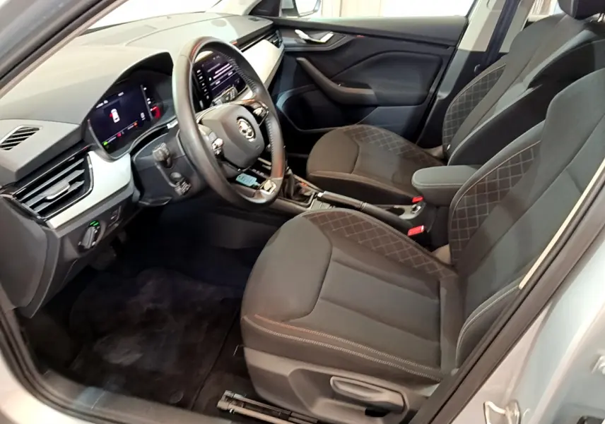 Intérieur avant droit du Skoda Kamiq gris clair 2022 avec sièges noirs et tableau de bord digital lumineux.