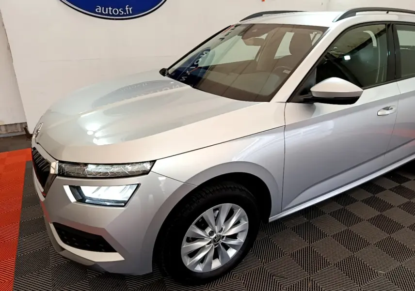 Vue 3/4 avant droit d'un Skoda Kamiq gris clair 2022 avec phares LED et jantes alliage visibles.