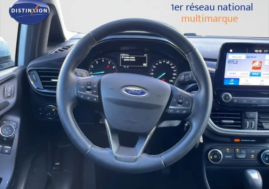 Vue intérieure centrée sur le volant noir de la Ford Fiesta 2020 avec tableau de bord et écran tactile visible.