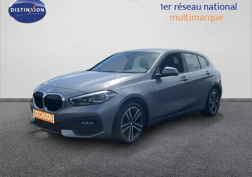 BMW Série 1 116i 2022 gris Frozen Pure Grey en 3/4 avant droit avec jantes bi-ton et calandre noire.