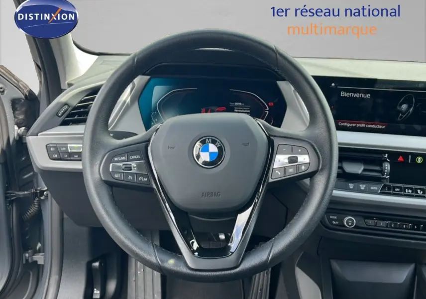 Vue intérieure centrée sur le volant cuir noir et tableau de bord numérique de la BMW Série 1 116i 2022 gris Frozen Pure.