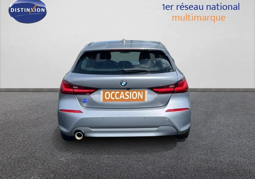 Vue arrière d'une BMW Série 1 116i gris mat Frozen Pure Grey avec feu arrière LED et sortie d'échappement côté gauche.