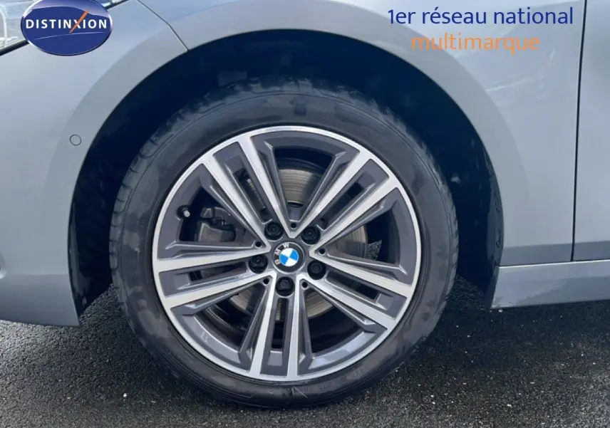Gros plan sur la roue avant gauche d’une BMW Série 1 116i 2022 en gris Frozen Pure avec jante alliage bicolore.