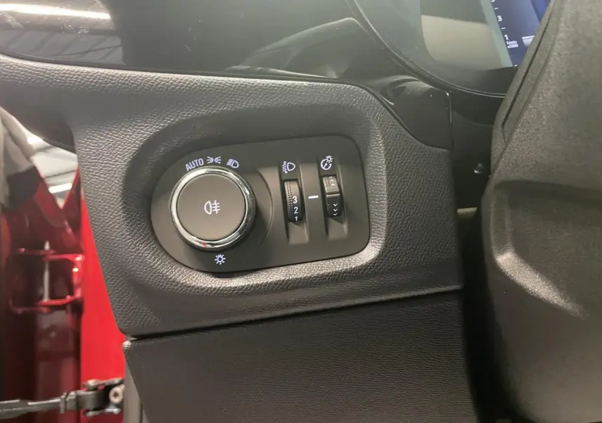 Détail du panneau de commandes d'éclairage à gauche du volant dans une Opel Corsa rouge, version 2026.