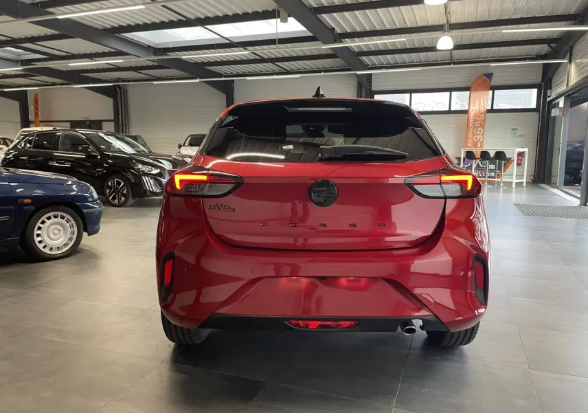 Vue arrière d'une Opel Corsa rouge métallisée avec feux LED allumés dans un showroom.