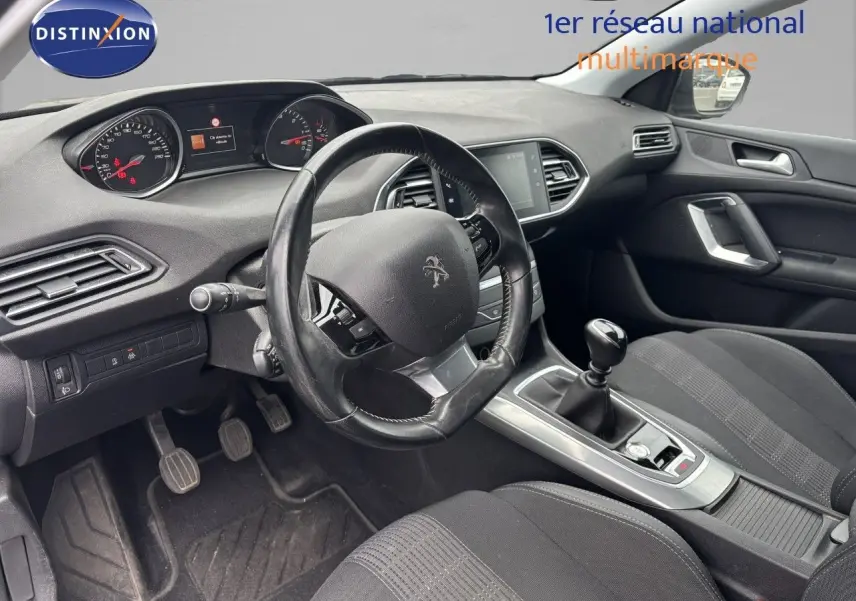 Vue intérieure côté conducteur de la Peugeot 308 1.5 BlueHDI 130 Allure avec volant cuir et boîte manuelle noire.