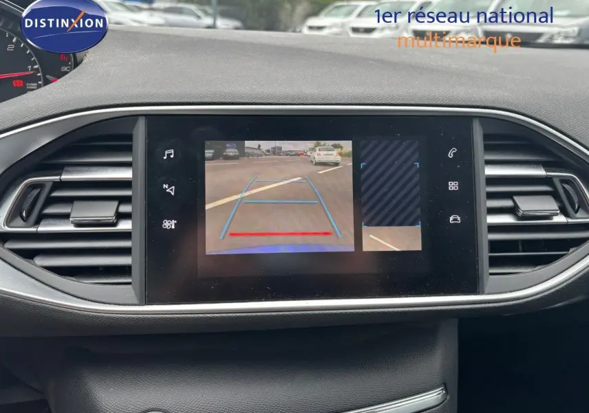 Écran central affichant la caméra de recul d'une Peugeot 308 Bleu Magnetic vue de l'intérieur côté tableau de bord.