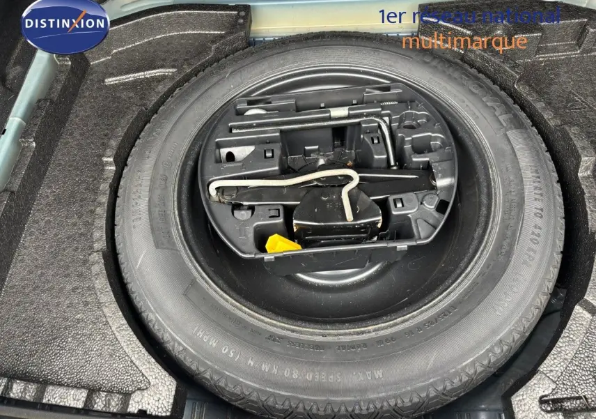 Roue de secours et outils de bord dans le coffre d'une Peugeot 308 Bleu Magnetic, vue en plongée rapprochée.