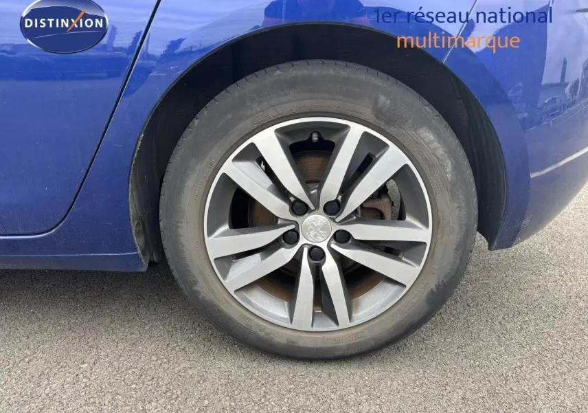 Gros plan sur la roue arrière droite d'une Peugeot 308 Bleu Magnetic, mettant en valeur la jante alliage distinctive.