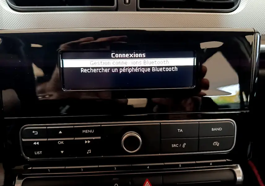 Gros plan sur l’écran central noir brillant de la Citroën C3 blanc, affichant le menu Bluetooth et les commandes audio.