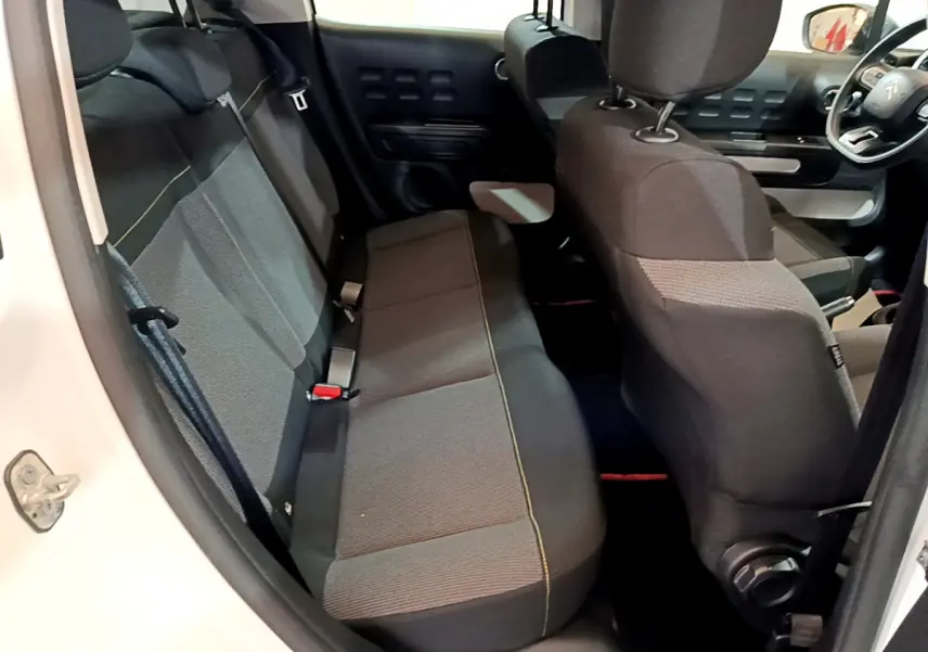 Vue intérieure côté arrière gauche du Citroën C3 blanc, montrant la banquette arrière et le siège avant côté conducteur.