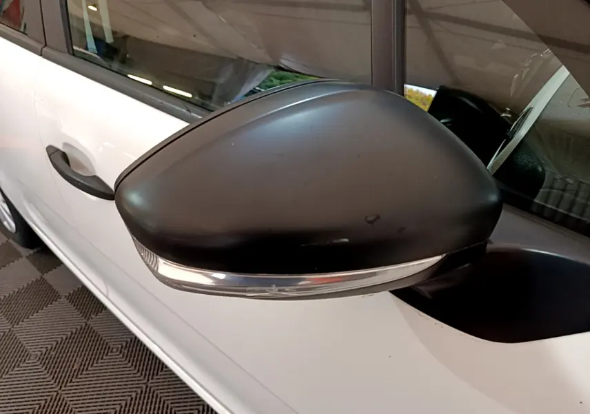 Gros plan sur le rétroviseur noir côté gauche d'une Citroën C3 blanche, avec clignotant intégré visible.