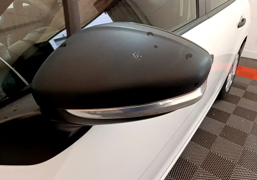 Gros plan sur le rétroviseur noir côté conducteur d'une Citroën C3 blanche vue de profil gauche.