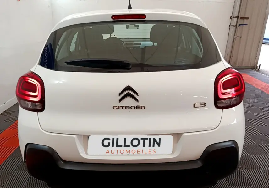Vue arrière d'une Citroën C3 blanche de 2018 avec feux arrière allumés dans un garage fermé.