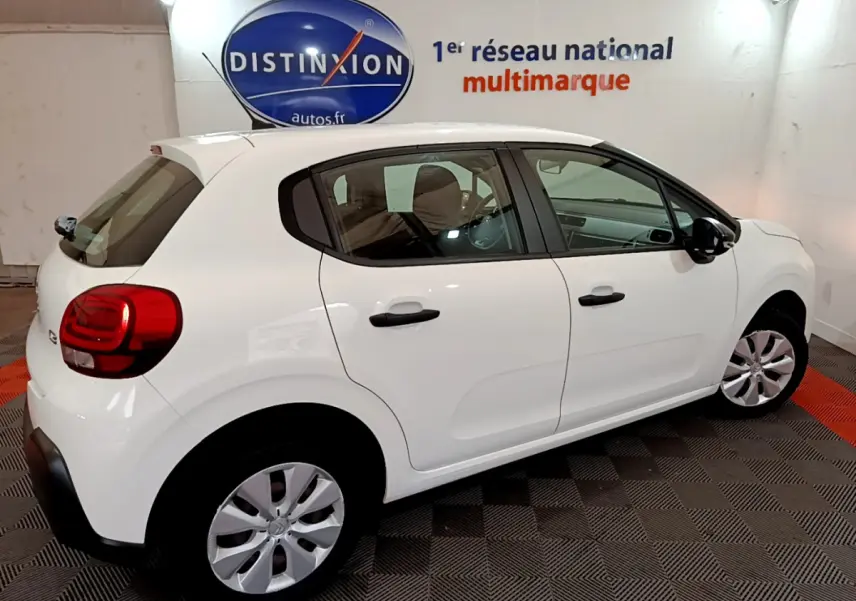 Citroën C3 blanche vue de profil droit en intérieur, avec poignées et rétroviseurs noirs contrastants.
