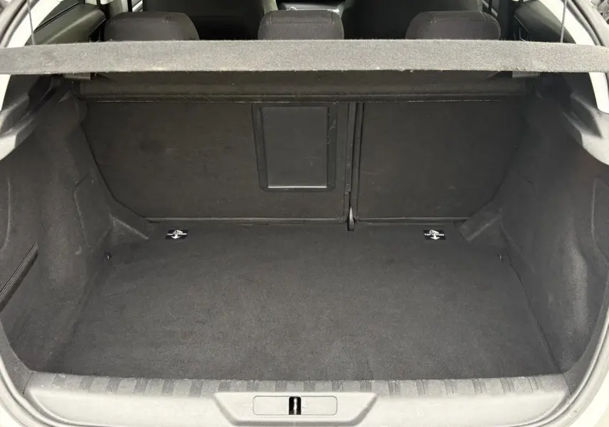 Vue du coffre ouvert d'une Peugeot 308 blanc nacré, montrant un espace de rangement propre et spacieux.