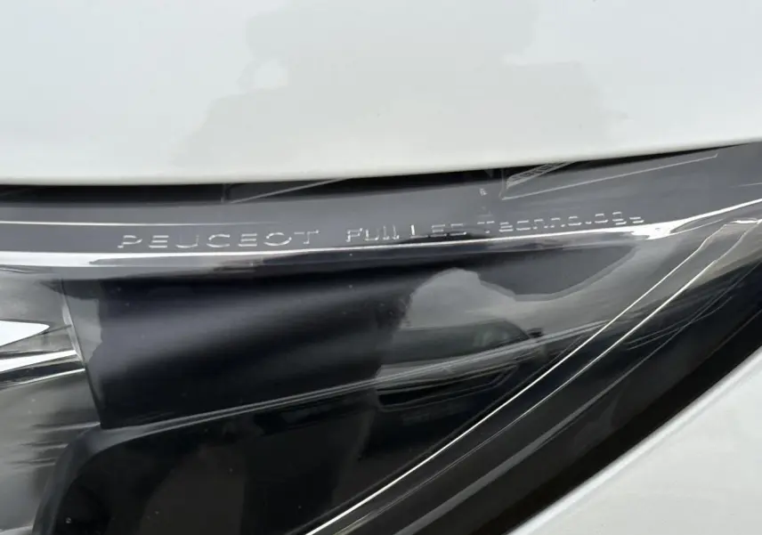 Gros plan sur le projecteur avant droit blanc nacré de la Peugeot 308 avec inscription Full LED Technology visible.