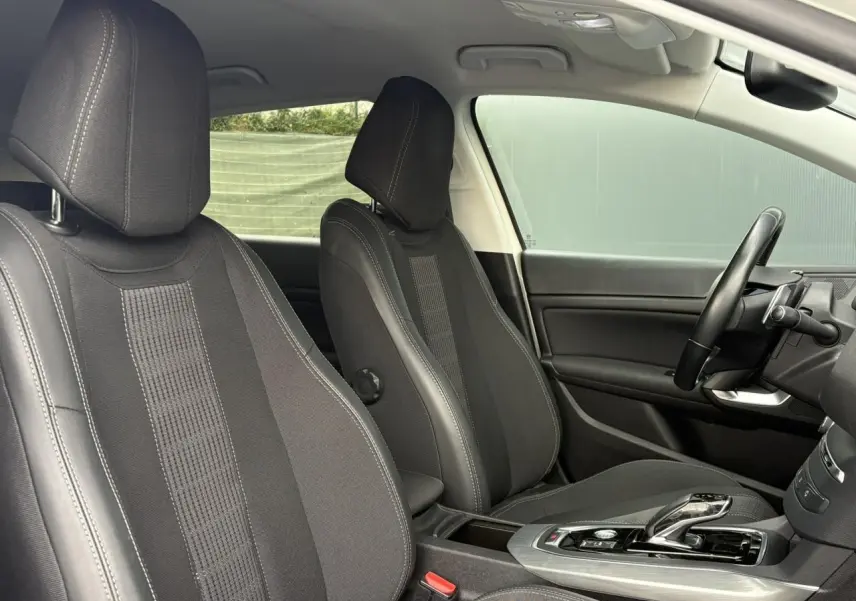 Vue intérieure côté conducteur de la Peugeot 308 2019 avec sièges noirs, volant cuir et console centrale moderne.