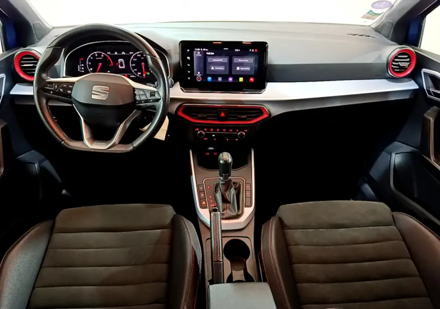 Vue intérieure avant du tableau de bord et volant de la SEAT Arona 2022, avec touches rouges et écran tactile central.