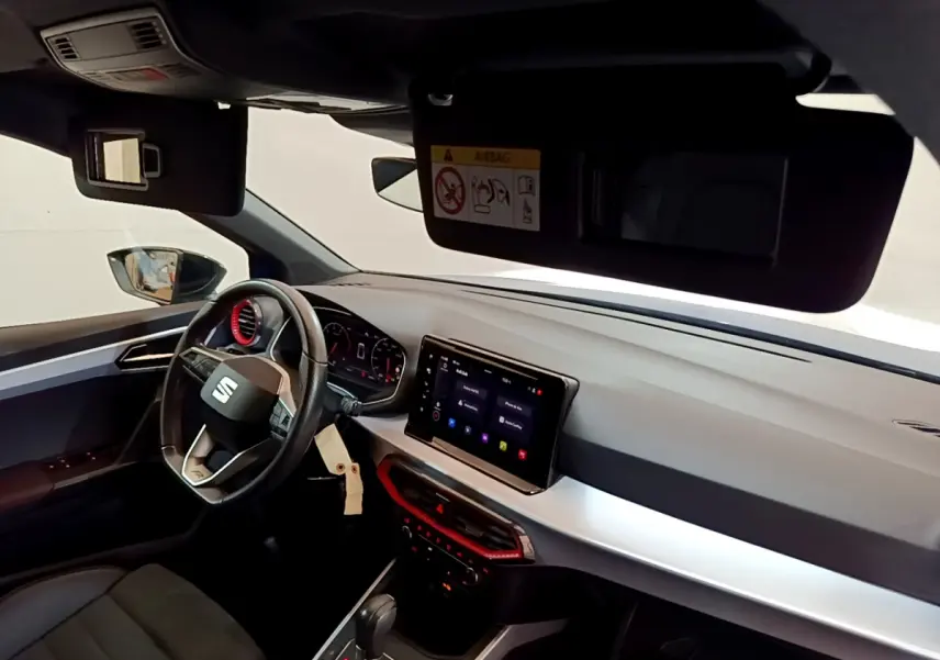 Intérieur de la SEAT Arona 2022, vue côté conducteur, tableau de bord moderne avec écran tactile et volant cuir.