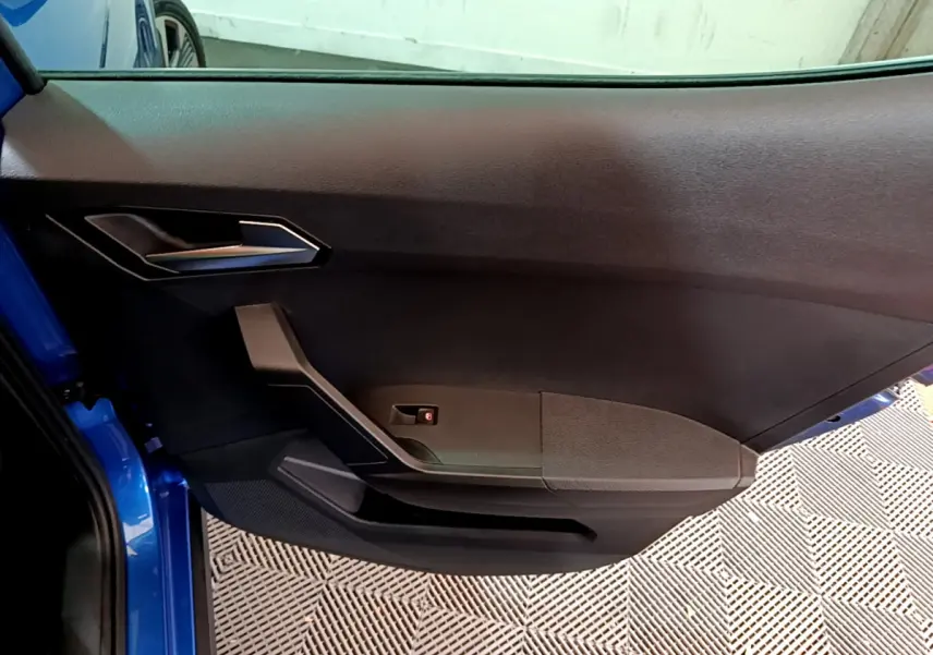 Vue rapprochée de la porte avant gauche bleu vif du SEAT Arona 2022 avec garniture noire et poignée argentée.