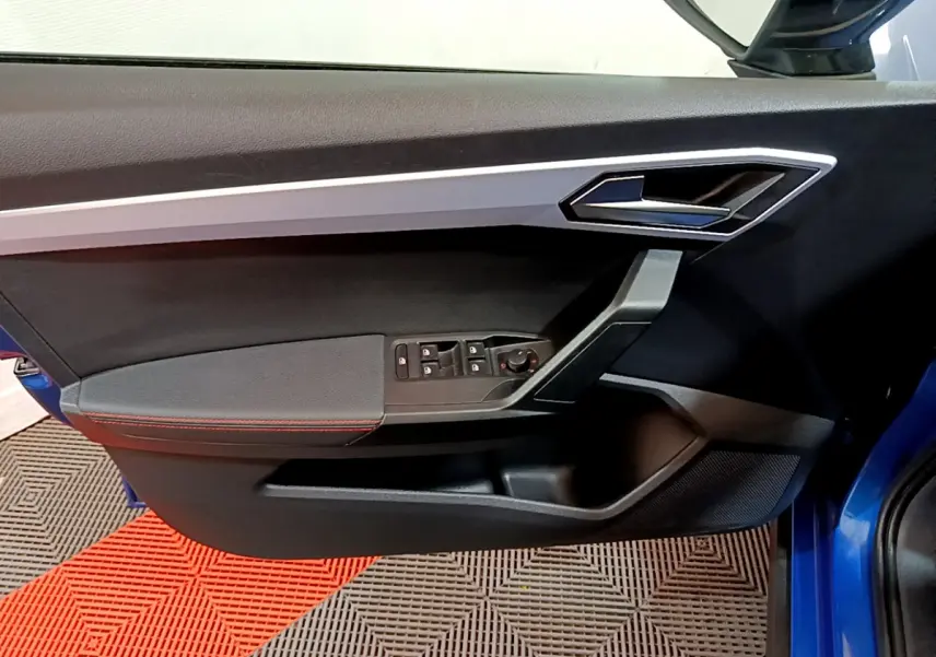 Vue rapprochée de la porte avant gauche bleu du SEAT Arona 2022 avec commandes de vitres et poignée argentée.