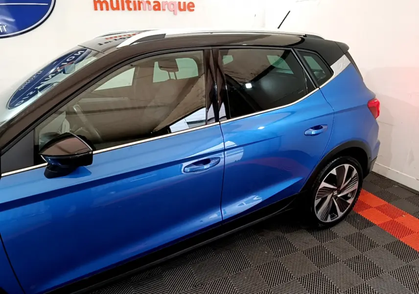 Vue latérale côté gauche du SEAT Arona bleu 2022 avec toit noir et jantes alliage distinctives.