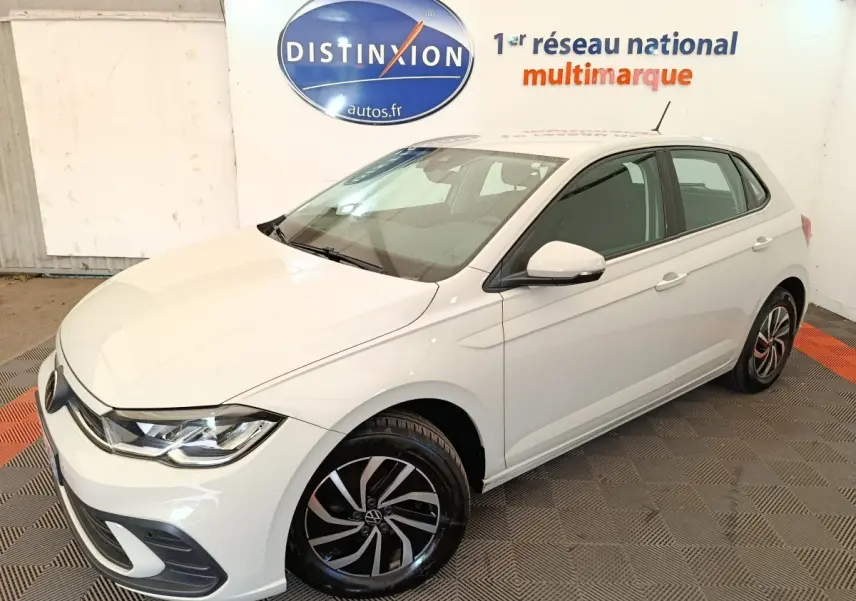 Vue 3/4 avant droite d'une Volkswagen Polo blanche avec jantes alliage noires et détails chromés dans un showroom.