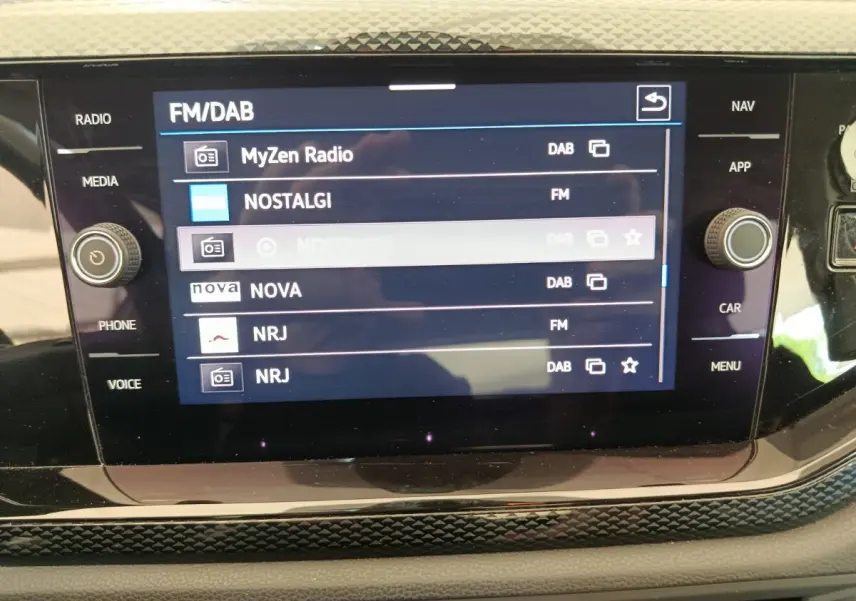 Écran tactile central de la Volkswagen Polo 2023 affichant les stations radio FM/DAB avec commandes autour.