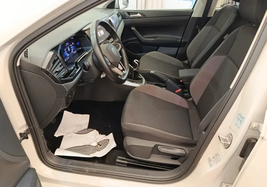Vue intérieure côté conducteur de la Volkswagen Polo gris clair 2023, montrant le volant multifonctions et les sièges tissu noirs.