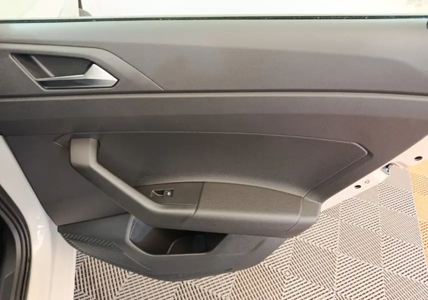 Vue intérieure de la porte avant gauche d'une Volkswagen Polo gris clair, avec poignée et bouton de verrouillage.