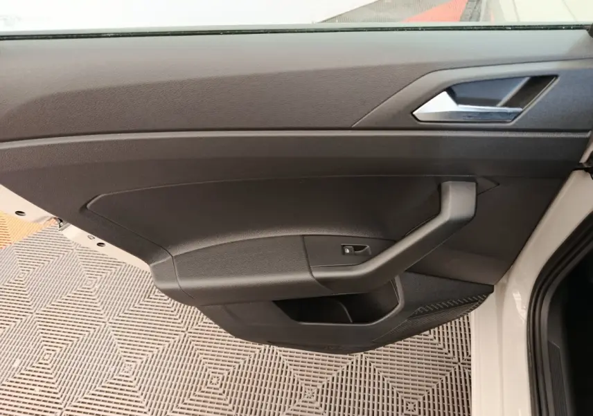 Vue rapprochée de la porte intérieure côté conducteur de la Volkswagen Polo 2023, avec garniture noire et poignée angulaire.