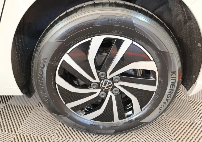 Gros plan sur la roue avant droite d'une Volkswagen Polo gris clair avec jante alliage noire et argentée.