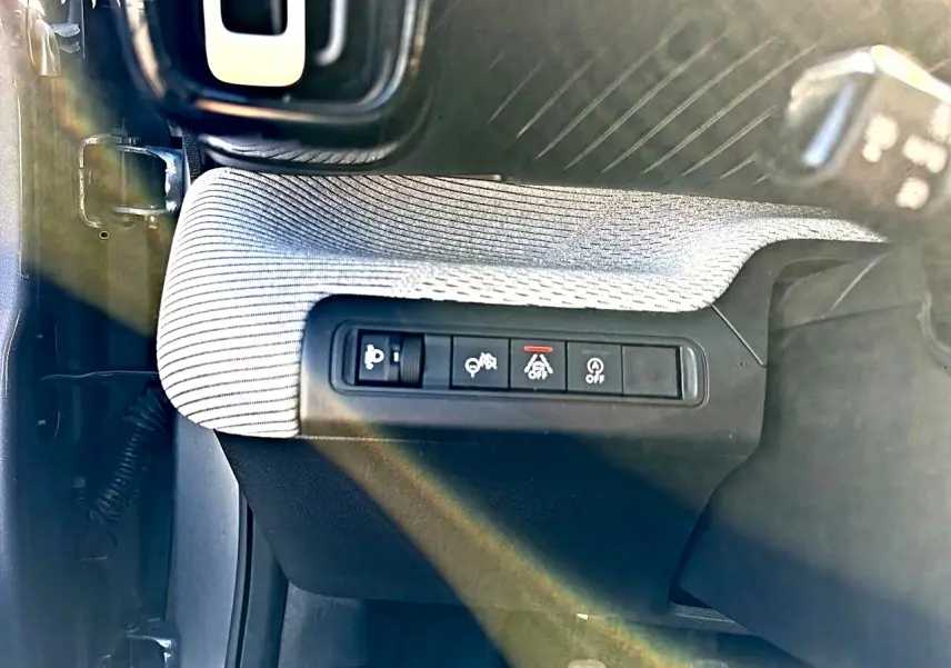 Vue rapprochée des commandes de sécurité côté gauche d’un Citroën C3 2025, tissu gris et plastique noir.