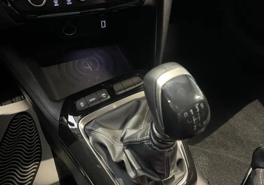 Gros plan sur la commande de la boîte manuelle noire et le chargeur à induction dans l’habitacle de l’Opel Corsa gris.