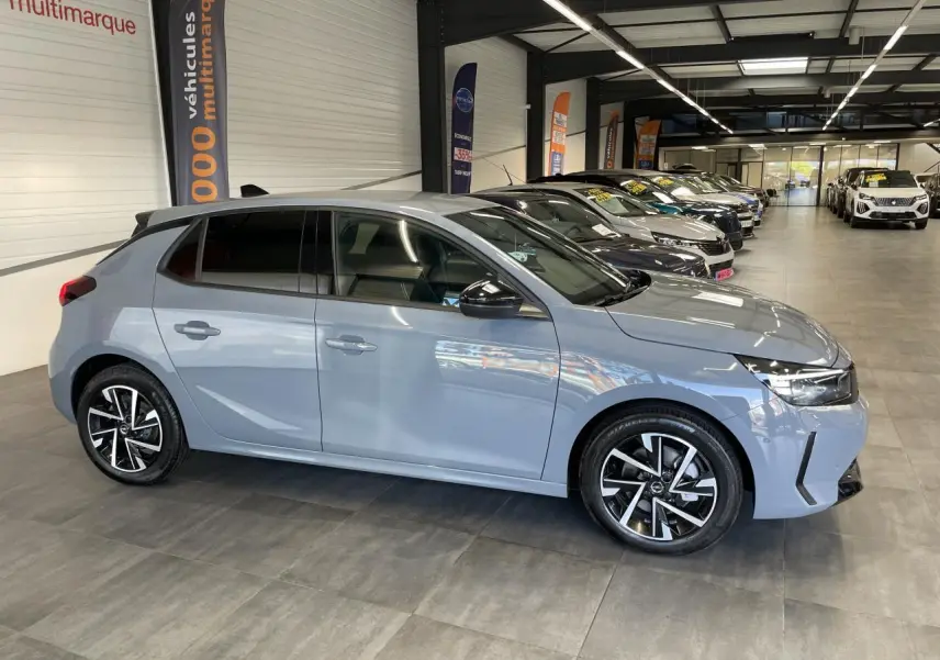 Opel Corsa gris clair vue de profil côté droit, avec jantes alliage noires et vitres arrière surteintées.